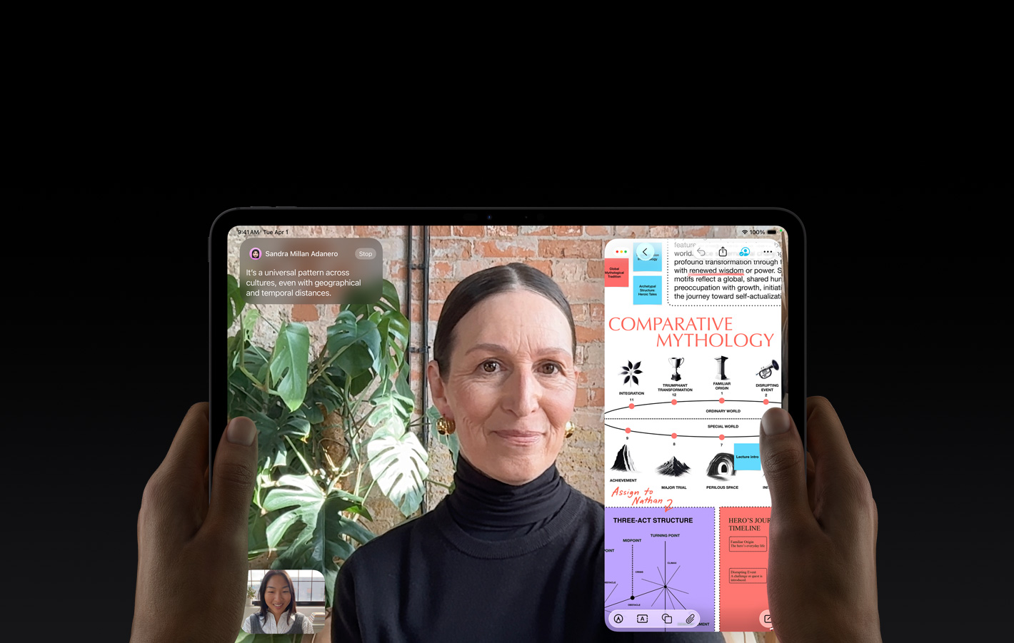iPad Pro, front exterior, space black colour, left and right hands holding in landscape orientation, rounded corners, black display bezel, display showing a FaceTime conversation being live translated, and an educational app showing a presentation of 'Comparative Mythology' with text, diagrams, and handwritten notes
