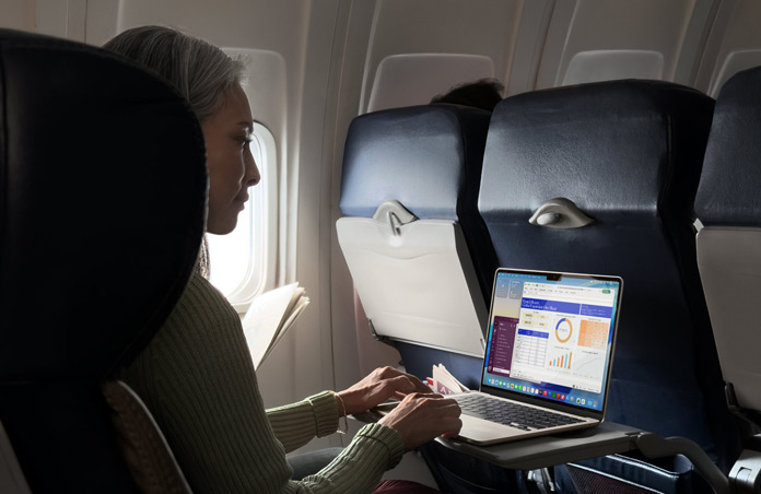 Iemand die in een vliegtuigstoel op een MacBook Air werkt