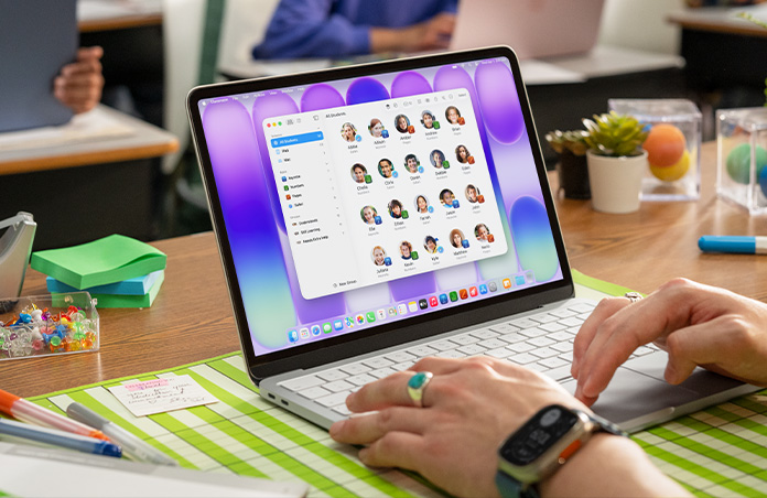 ผู้สอนนั่งอยู่กับ Mac ที่เปิดอยู่โดยที่แอปห้องเรียนแสดงรายชื่อนักเรียนทั้งหมดบนหน้าจอ