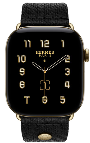 Apple Watch Hermès Series 12, Clou de Selle analog watch face (hour, minute, and second hands, complications: lunar phase, date), titanium case, radiant gold color, right side exterior, Digital Crown, side button, paired with Noir Satin Clou de Selle band, smooth black satin webbing with radiant gold hardware that matches the watch case