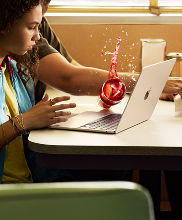 Una persona che si trova al ristorante versa per sbaglio una bevanda ghiacciata su un MacBook aperto