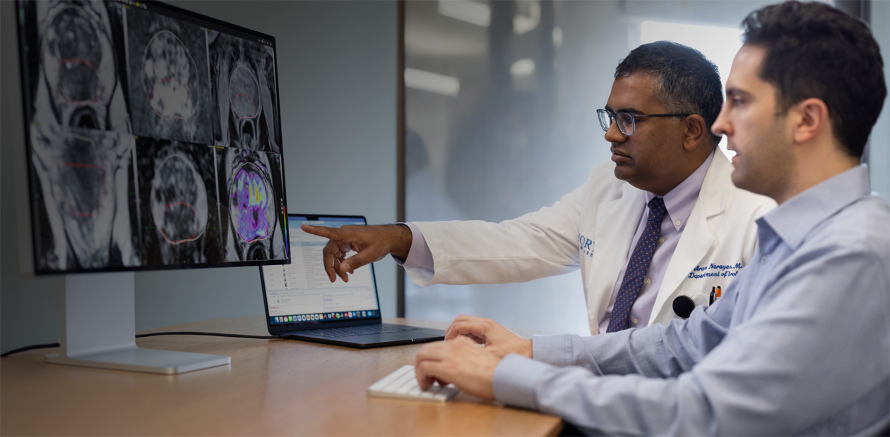 Twee artsen kijken samen naar radiologiebeelden op een iMac.