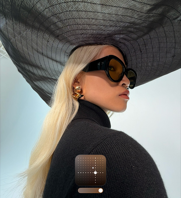 Potret seorang perempuan memakai topi hitam brim lebar menunjukkan Gaya Fotografi Cerah, yang mencerahkan foto dalam kondisi pencahayaan rendah atau mode Malam