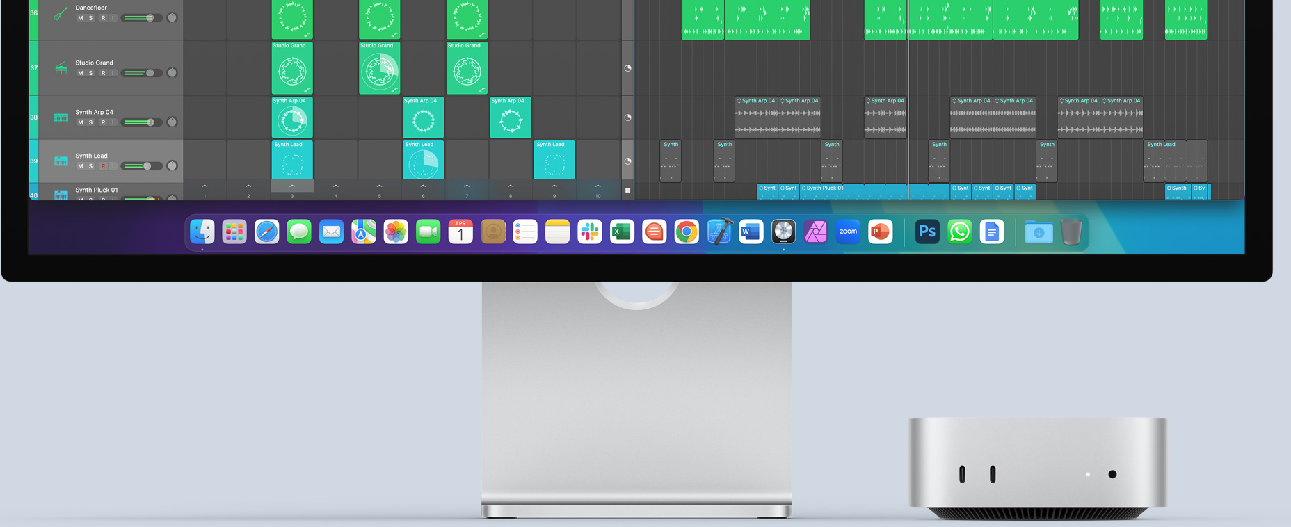 Hõbedase Mac mini esivaade, kus nähtaval on eesmised liidesed ja indikaatortuli, mahtudes kenasti Maci monitori alla, kus on kuvatud värviline ekraan ja rakenduste ikoonid dokis